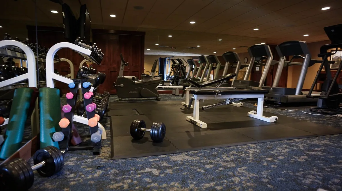 A well-equipped fitness center featuring treadmills, dumbbells, and a weight bench. The space feels modern, clean, and inviting, with ample light and a motivational atmosphere for workouts or wellness routines.
