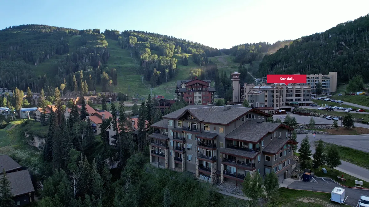 A panoramic view of the resort buildings nestled among trees with majestic mountains rising in the background. The area’s natural beauty is on display, inviting guests to explore hiking trails or enjoy peaceful moments in nature.